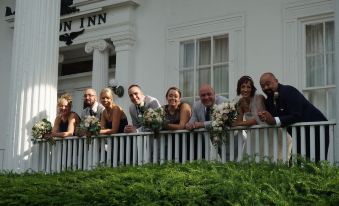 a group of people posing for a photo on the balcony of the white house , with one person holding a bouquet of flowers at Avon Inn