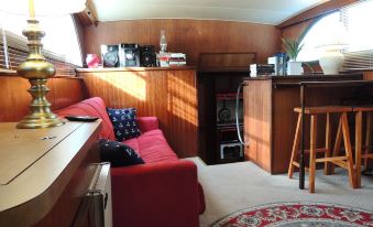 a cozy living room with wooden walls , a red couch , and a dining table in the background at Cookie B