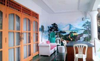 a cozy living room with white furniture , an orange door , and a wall mural depicting a mountainous landscape at Mason Residence Syariah Ciawi