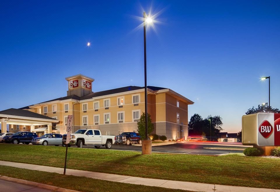 a large hotel with a parking lot in front of it , surrounded by cars and trees at Best Western Plus Pontoon Beach