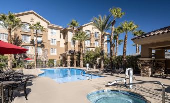 a large swimming pool and surrounding area of an apartment building , including palm trees and benches at Hilton Garden Inn Las Vegas Strip South