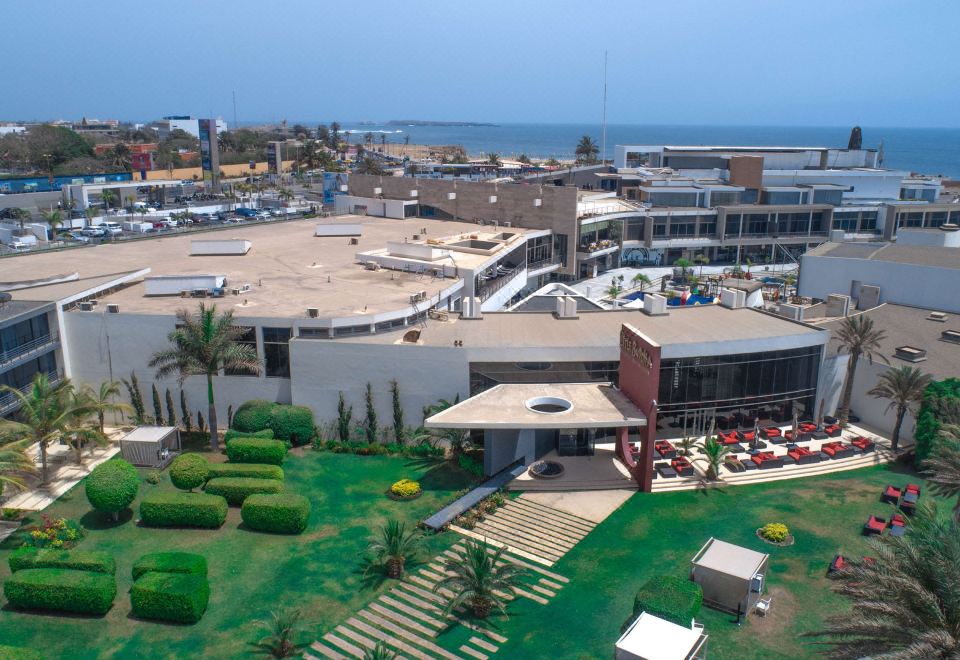 a bird 's eye view of a building with palm trees and green grass , overlooking the ocean at Radisson Blu Hotel, Dakar Sea Plaza