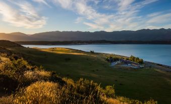 a serene landscape of a lake surrounded by green hills and mountains under a cloudy sky at Lakestone Lodge