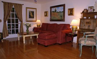 a living room with a red couch , two lamps , and framed pictures on the wall at Sabal Palm House Bed and Breakfast