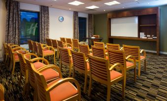 a conference room with rows of chairs arranged in a semicircle , and a projector screen on the wall at Holiday Inn Express Stevenage