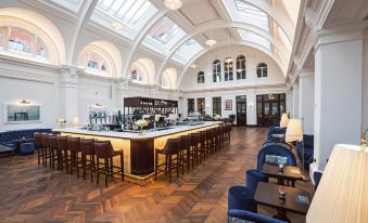 a large , well - lit room with a long bar and several chairs arranged around it , creating a cozy atmosphere at Titanic Hotel Belfast