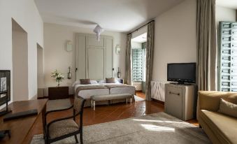 a modern hotel room with wooden flooring , white walls , and large windows , featuring a bed , tv , desk , and window at Parador de La Granja