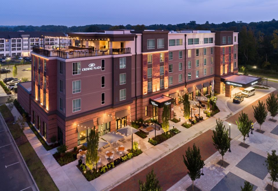 a large brick building with a restaurant in front of it , surrounded by trees and other buildings at Crowne Plaza North Augusta