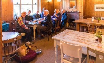 a group of people sitting at a dining table in a wooden house , with a dog nearby at Three Horseshoes Inn