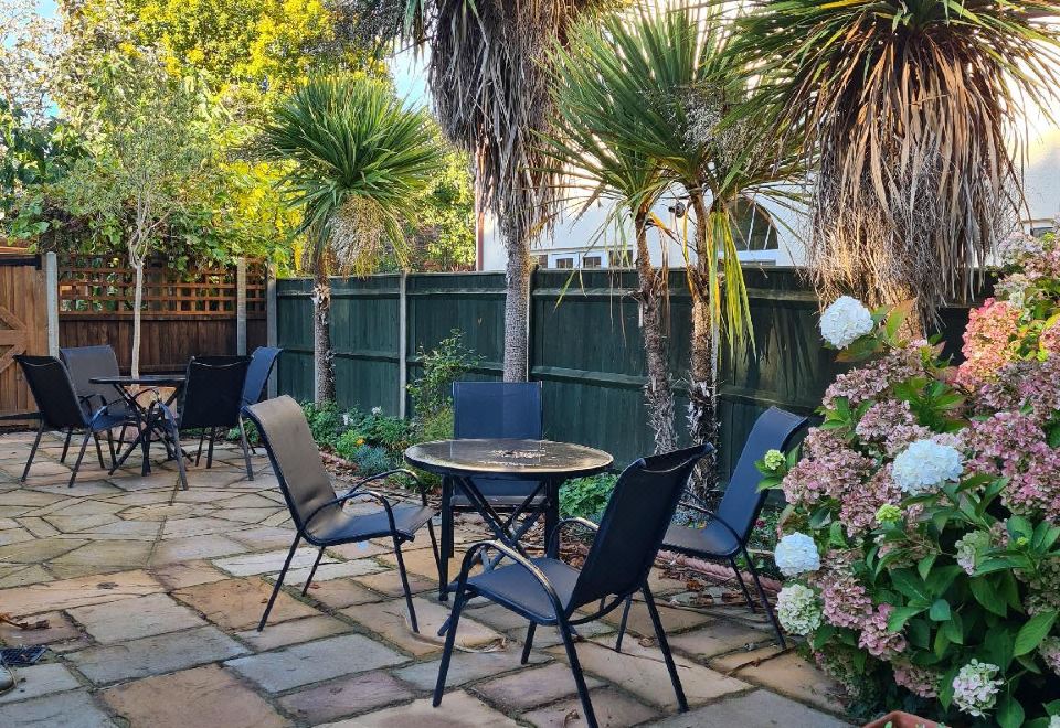 a patio with a table and chairs surrounded by potted plants , creating a pleasant outdoor space at Holm Oaks