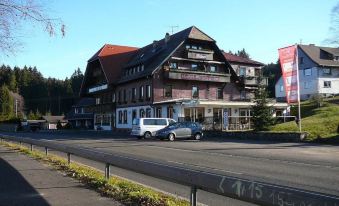 "a car is parked in front of a building with a red roof and the address "" 2 4 1 5 4 5 4 5 ""." at Hotel Faller