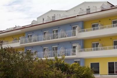 a multi - story building with blue and yellow exterior colors , balconies , and white railings , surrounded by greenery at Hotel Summery