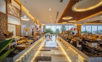 a large dining area with a long buffet table filled with various food items and utensils at Navada Beach Hotel