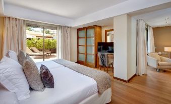 a large bedroom with a king - sized bed and a sliding glass door leading to a patio area at Protur Biomar Sensatori Resort