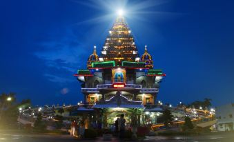 a tall , multi - tiered temple with a tall spire and many windows is illuminated by lights at night at Griya Hotel