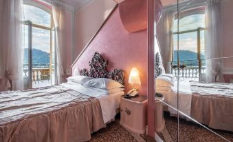 a pink bedroom with two beds , one on each side of the room , and a bathroom nearby at Grand Hotel Cadenabbia