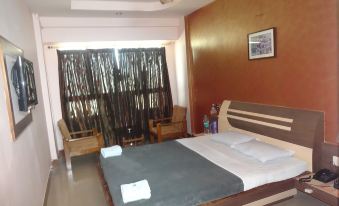 A bedroom with large windows and chairs in the middle, alongside an unidentifiable object at Hotel Sonali