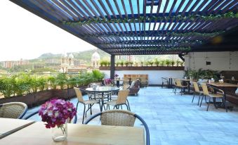 a rooftop patio with tables , chairs , and flowers is shown with a view of the city at Hotel Perlatto