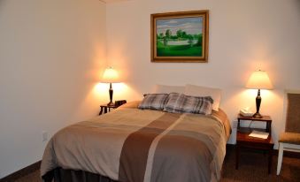 a well - lit bedroom with a bed , two lamps , and a painting on the wall , all arranged neatly at The Eis House