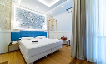 a modern bedroom with a blue and white color scheme , featuring a large bed , a tv , and a dresser at Hotel Palace