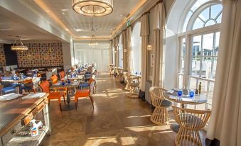 a large dining room with multiple tables and chairs arranged for a group of people to enjoy a meal together at Harbour Hotel & Spa Christchurch