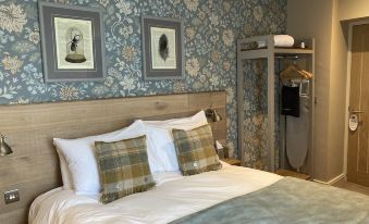 a hotel room with a king - sized bed and floral wallpaper , creating a cozy and inviting atmosphere at Old Swan