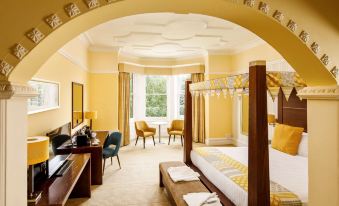 a large bed with a canopy is in the middle of a room with yellow walls and a desk at Mercure Hull Grange Park Hotel