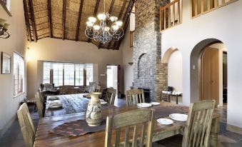 a large dining room with a wooden table and chairs , a chandelier hanging from the ceiling , and a fireplace at The Cottage