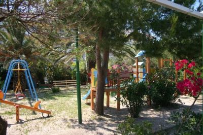 a park with a playground surrounded by trees , benches , and a picnic table for children to play on at Hotel Summery