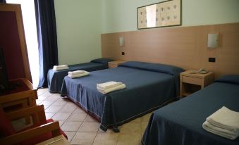 a hotel room with three beds , one on the left , one in the middle , and one on the right side of the room at Hotel Miramare