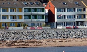 a beach with a row of colorful houses on the shore , and a boat in the water at Rungholt