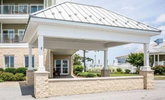 a white house with a large open porch and a clear blue sky in the background at Island Inn & Suites, Ascend Hotel Collection