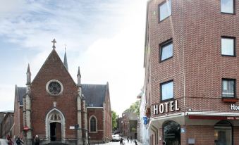 a brick building with a cross on the front is situated in a parking lot at Hotel the Shepherd