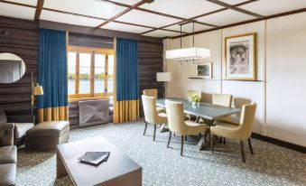 a living room with a dining table and chairs , a couch , and a window with blue curtains at Fairmont le Château Montebello