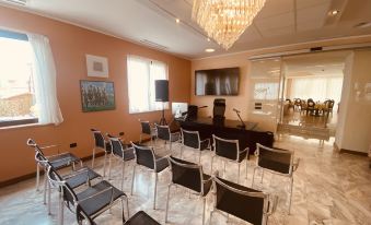 a conference room with rows of chairs and a large screen , under a crystal chandelier at Green Park Hotel