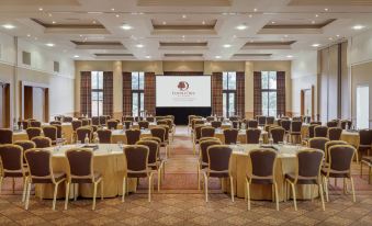 a large conference room with rows of chairs and tables , a projector screen at the front at DoubleTree by Hilton Glasgow Westerwood Spa & Golf Resort