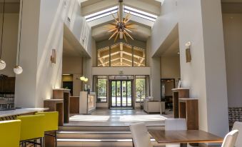 a large , well - lit lobby with a wooden floor and high ceilings , featuring a staircase leading to the second floor at Holiday Inn Clarkston - Lewiston