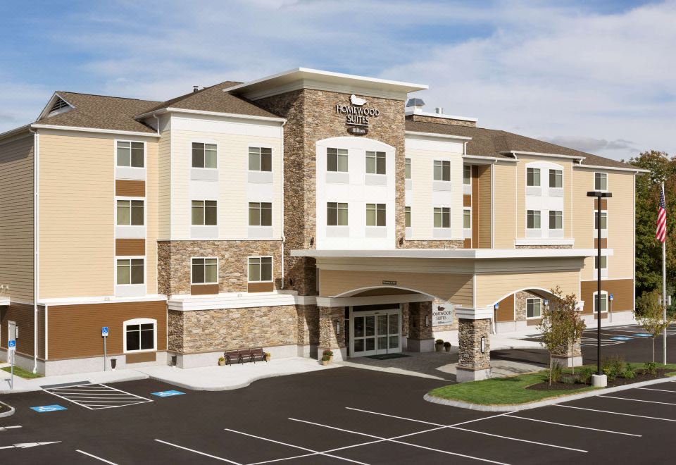 a large building with a brown and white facade is surrounded by a parking lot at Homewood Suites by Hilton Augusta, ME