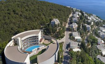 aerial view of a resort surrounded by trees and the ocean , with a large swimming pool visible in the center at Duja Bodrum