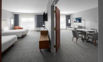 a modern hotel room with two beds , a dining table , and a tv , all arranged in a spacious living area at Courtyard Tampa Oldsmar