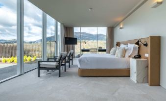 a modern bedroom with a king - sized bed , chairs , and a large window overlooking a mountain view at Octant Douro