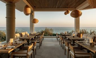 a restaurant with wooden tables and chairs is situated near the ocean , where it has been transformed into a cozy dining area at Villa Le Blanc Gran Melia