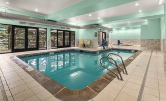 an indoor swimming pool with a diving board and ladder , surrounded by green walls and white tiles at Holiday Inn & Suites Bothell