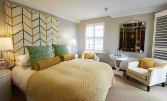 a cozy bedroom with a large bed , a chair , and a mirror on the wall at Harbour Hotel & Spa Christchurch