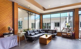 a modern living room with a black leather couch , wooden coffee table , and large windows at Baan Tah on the Sea