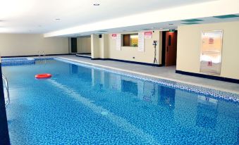 an indoor swimming pool with a blue tiled floor , surrounded by white walls and red signs at Nooh Tower