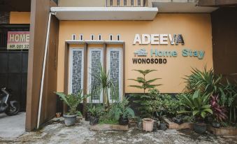 "a building with the words "" adeeva home stay wonosobo "" written on the side , surrounded by plants and potted trees" at RedDoorz Syariah @ Jalan Dieng