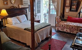 a cozy bedroom with a four - poster bed , a couch , and a tv . also a dining table in the room at Town's Inn