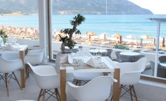 a dining room with white chairs and tables set up for a meal , overlooking a beach at Konstantinos Palace