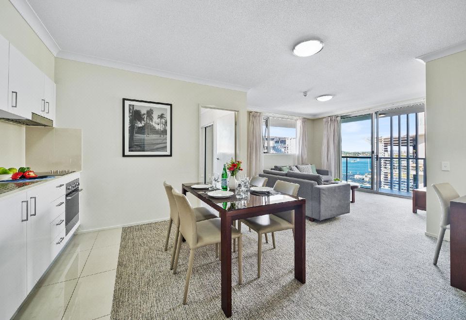 a modern living room and dining area with a view of the ocean , featuring a gray couch , wooden table , chairs , and a sliding glass at Quest Breakfast Creek